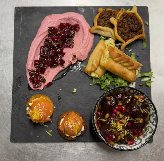 Composition de mezzés colorés avec betterave, pâtisseries salées et grenade sur ardoise